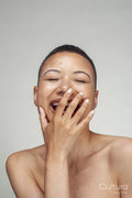 Studio portrait of shirtless woman laughing with eyes closed