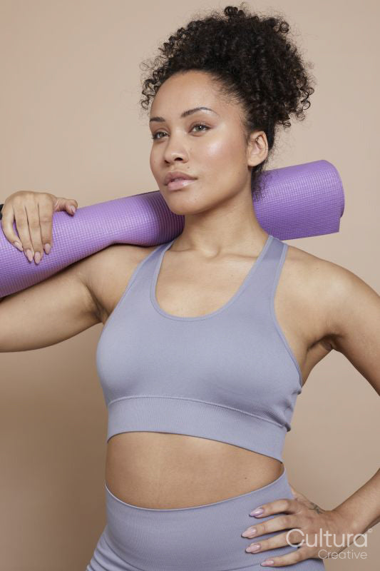 Studio portrait of athletic woman with yoga mat