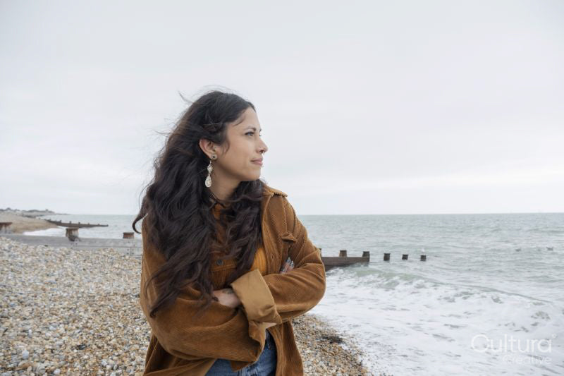 Thoughtful woman looking at sea while standing on beach on cloudy day