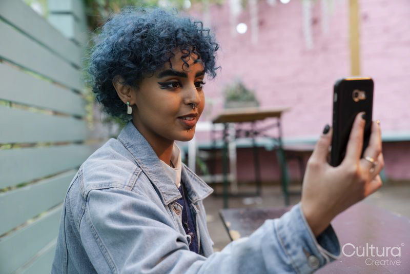 Young woman with blue hair using phone