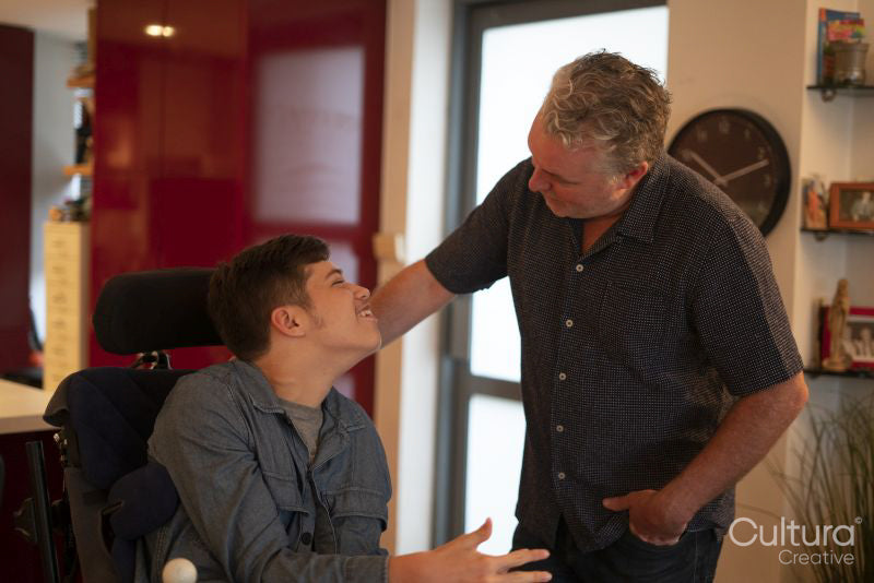 Father talking with disabled son at home