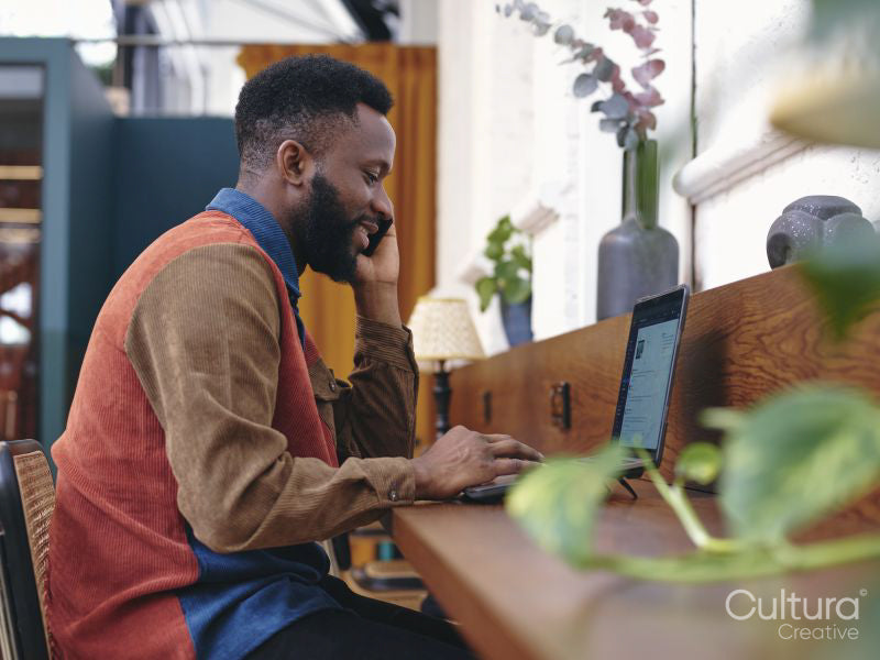 Smiling businessman using smart phone and laptop