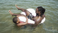 Father and son playing in inflatable ring in sea