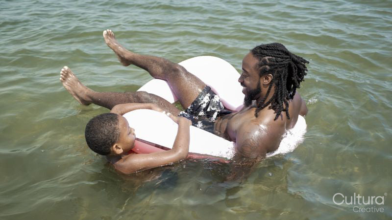 Father and son playing in inflatable ring in sea