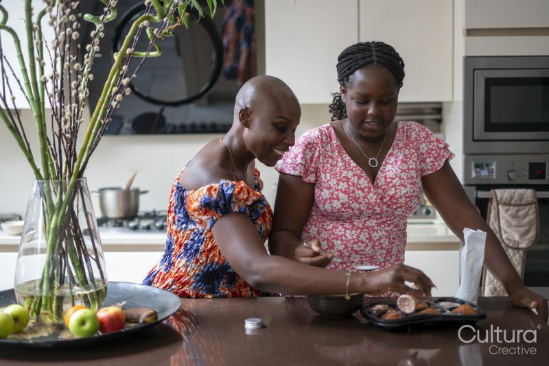 Smiling mother and teenage daughter baking muffins in kitchen