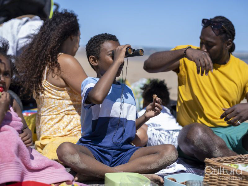 Boy looking through binoculars on beach