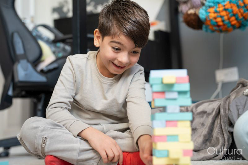 Boy sitting on floor and playing with toy blocks