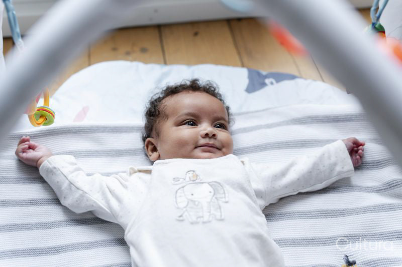 Baby girl lying on play mat at home