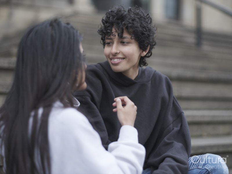 Smiling female couple sitting on stairs in city