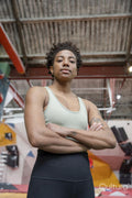 Portrait of serious woman standing with arms crossed in front of climbing wall