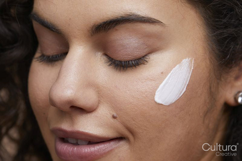 Close-up of young woman applying face cream