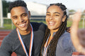Portrait of male and female athlete celebrating with medals