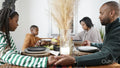 Family with children praying before Kwanzaa meal