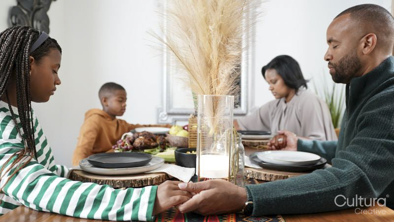 Family with children praying before Kwanzaa meal