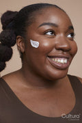 Studio shot of smiling young woman applying face cream
