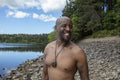 Portrait of smiling shirtless man on rocky lakeshore, Yorkshire, UK