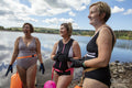 Female friends in swimsuits standing on rocky lakeshore, Yorkshire, UK