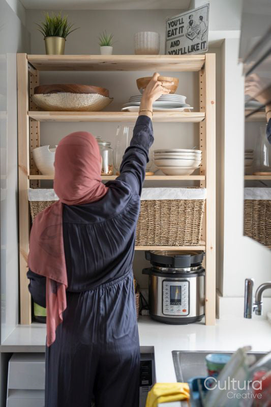 Woman in hijab putting dishes on shelf