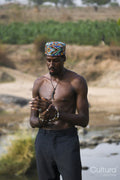 Portrait of young shirtless man wearing traditional hat