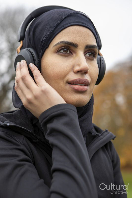 Smiling woman in hijab listening to music in park