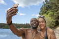 Smiling couple taking selfie on rocky lakeshore, Yorkshire, UK