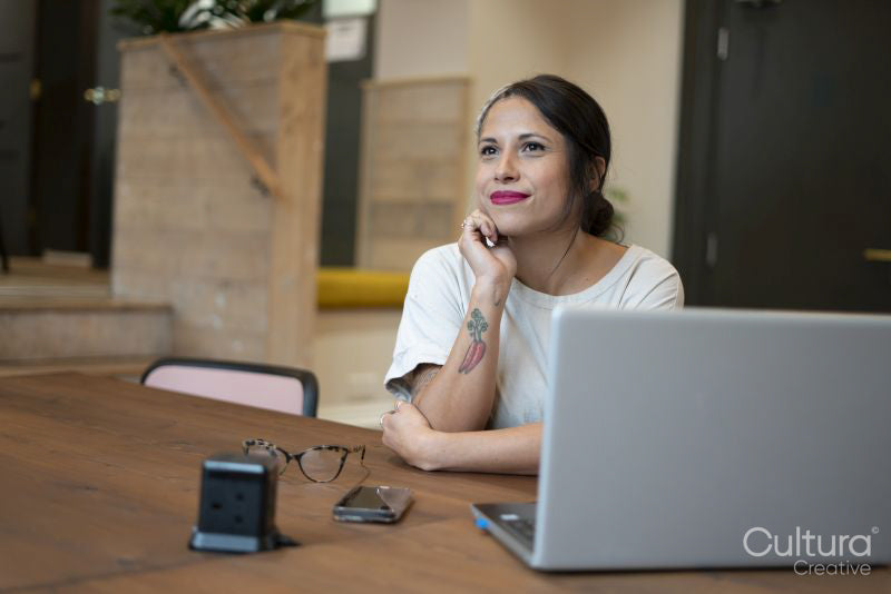 Smiling woman sitting in office with hand on chin