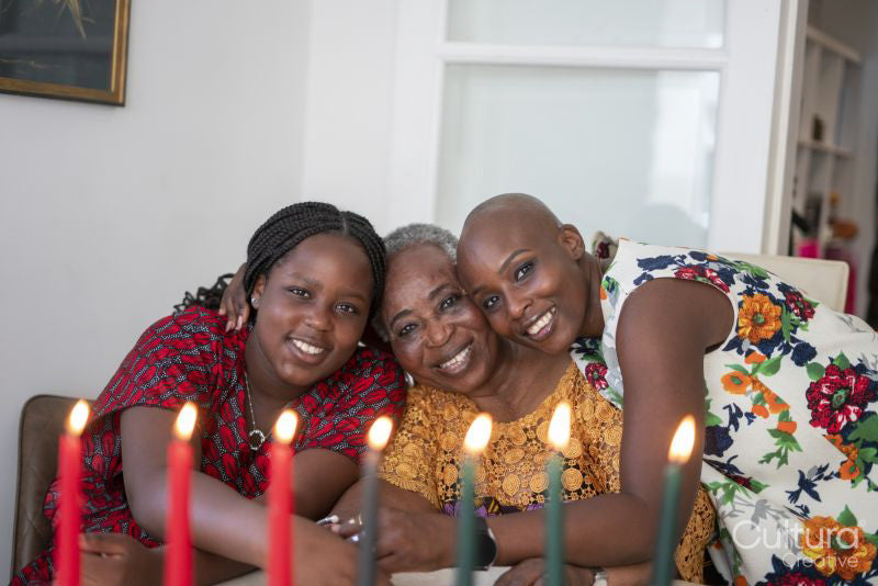 Teenage girl with mother and grandmother at table with Kwanzaa candles