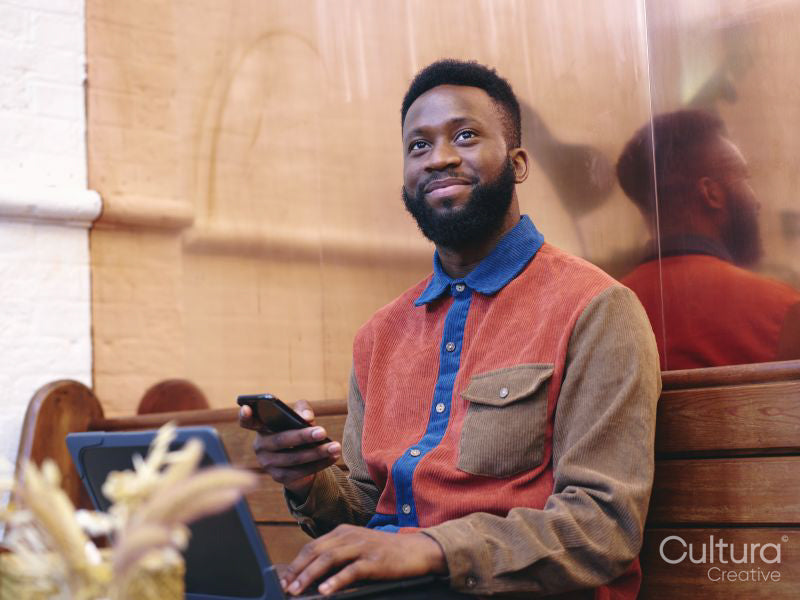 Smiling businessman using smart phone and laptop