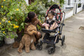 Mother going for walk with baby daughter in stroller and dog