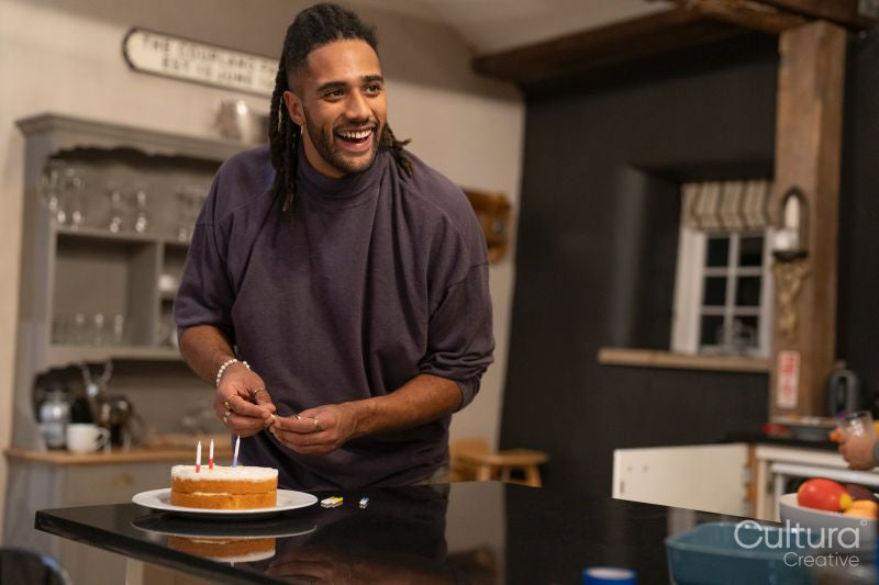 Smiling man placing candles on birthday cake