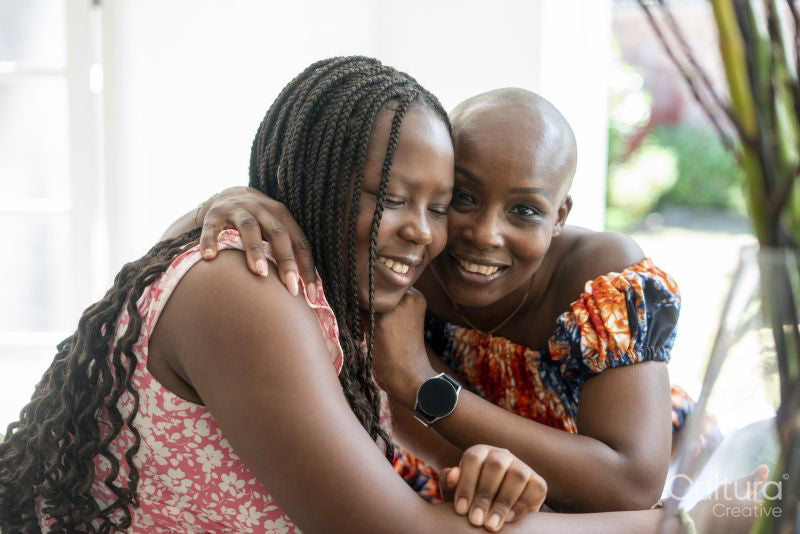 Smiling mother and teenage daughter embracing at table
