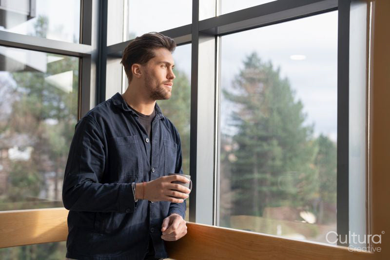 Businessman drinking coffee and looking through office window