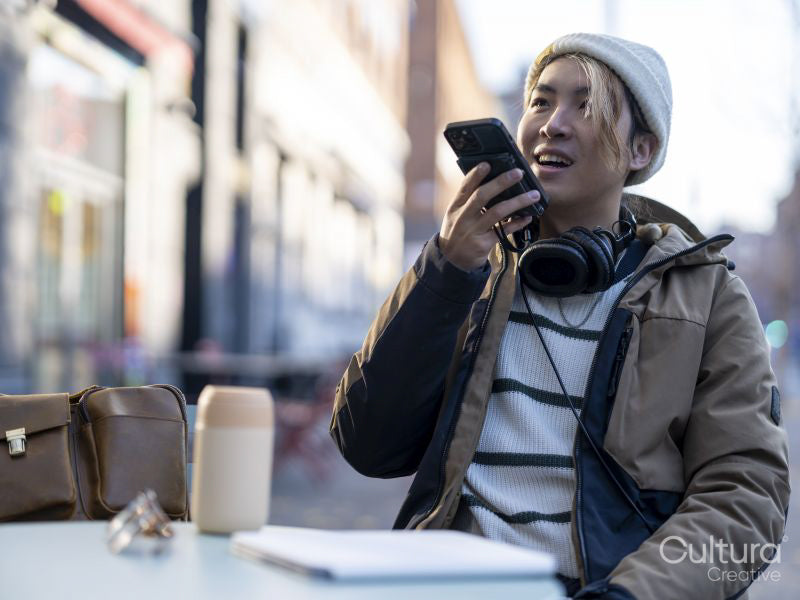 Man using smart phone while sitting at sidewalk cafe