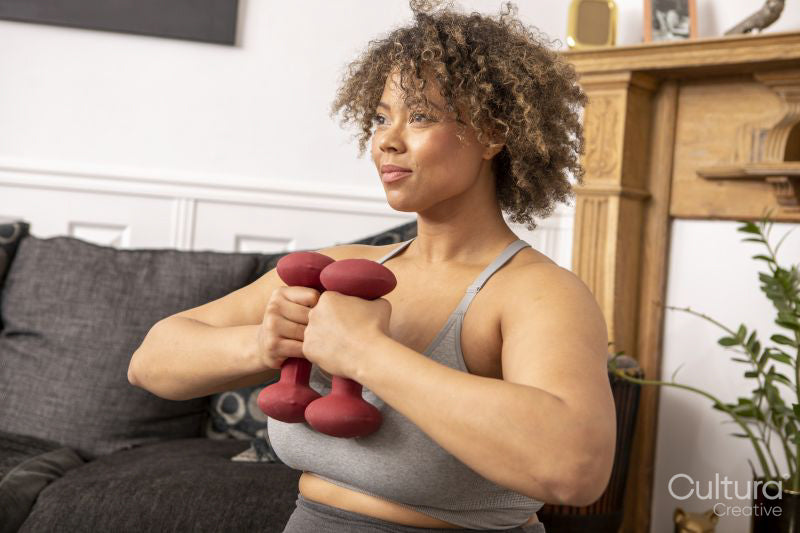 Woman exercising with dumbbells in living room