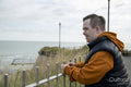 Man leaning on fence looking at sea coast