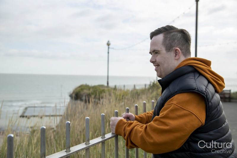 Man leaning on fence looking at sea coast