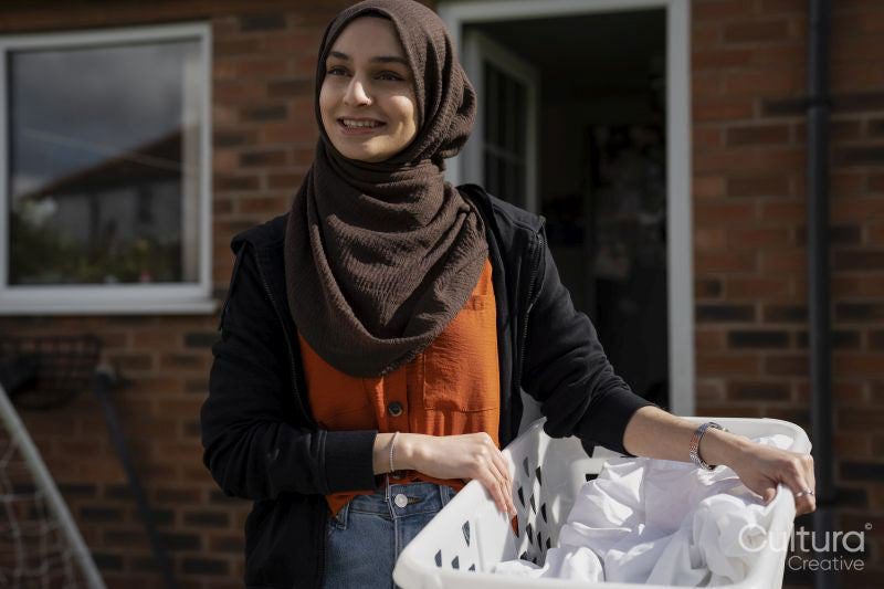 Woman wearing hijab carrying laundry basket
