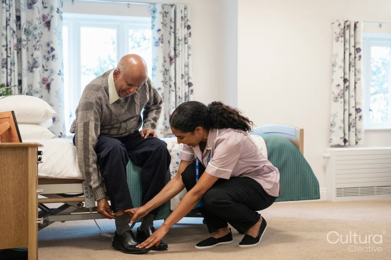 Nurse helping senior man to get dressed at nursing home