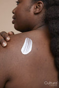 Studio shot of young woman applying moisturizer on back