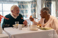 Smiling senior people eating meal in nursing home