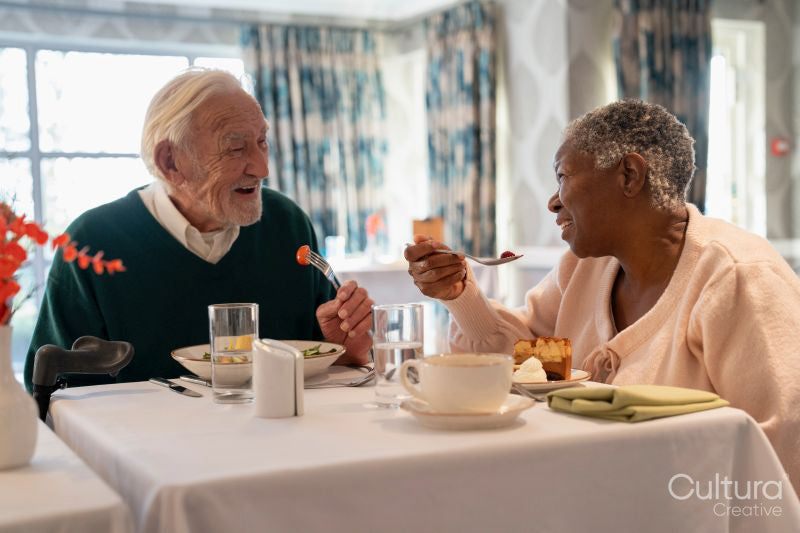 Smiling senior people eating meal in nursing home