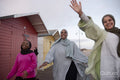 Cheerful Muslim friends walking next to beach huts