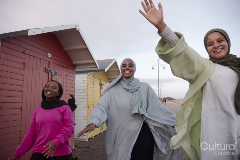 Cheerful Muslim friends walking next to beach huts