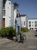 Woman walking with dog in residential district on sunny day