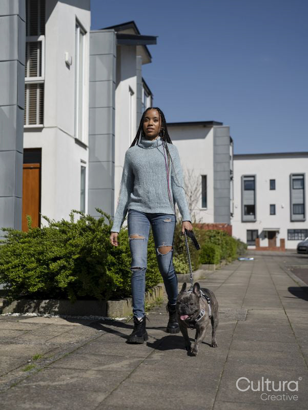 Woman walking with dog in residential district on sunny day