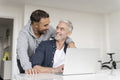 Male couple using laptop at home