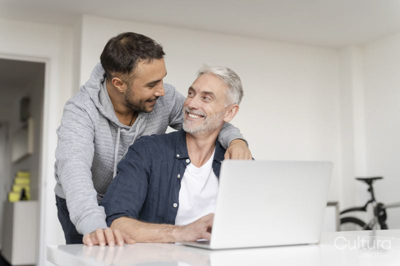 Male couple using laptop at home