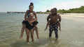 Smiling parents giving piggy back rides to children on beach