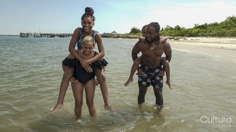 Smiling parents giving piggy back rides to children on beach