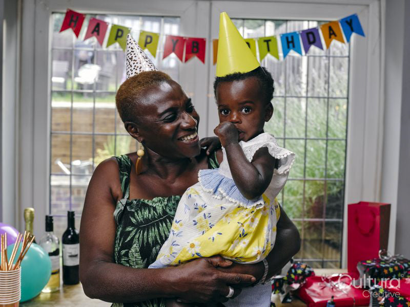 Grandmother holding baby granddaughter at birthday party